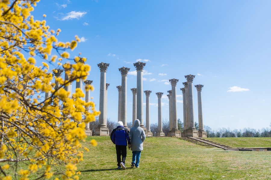 A couple in winter coats walks toward the Capitol Columns at the U.S. National Arboretum.